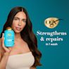 Woman holding Argan Oil of Morocco Conditioner. Strengthens and Repairs in 1 wash