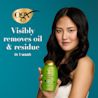 Woman holding Rosemary Mint Shampoo. Visibly removes oil & residue in 1 wash