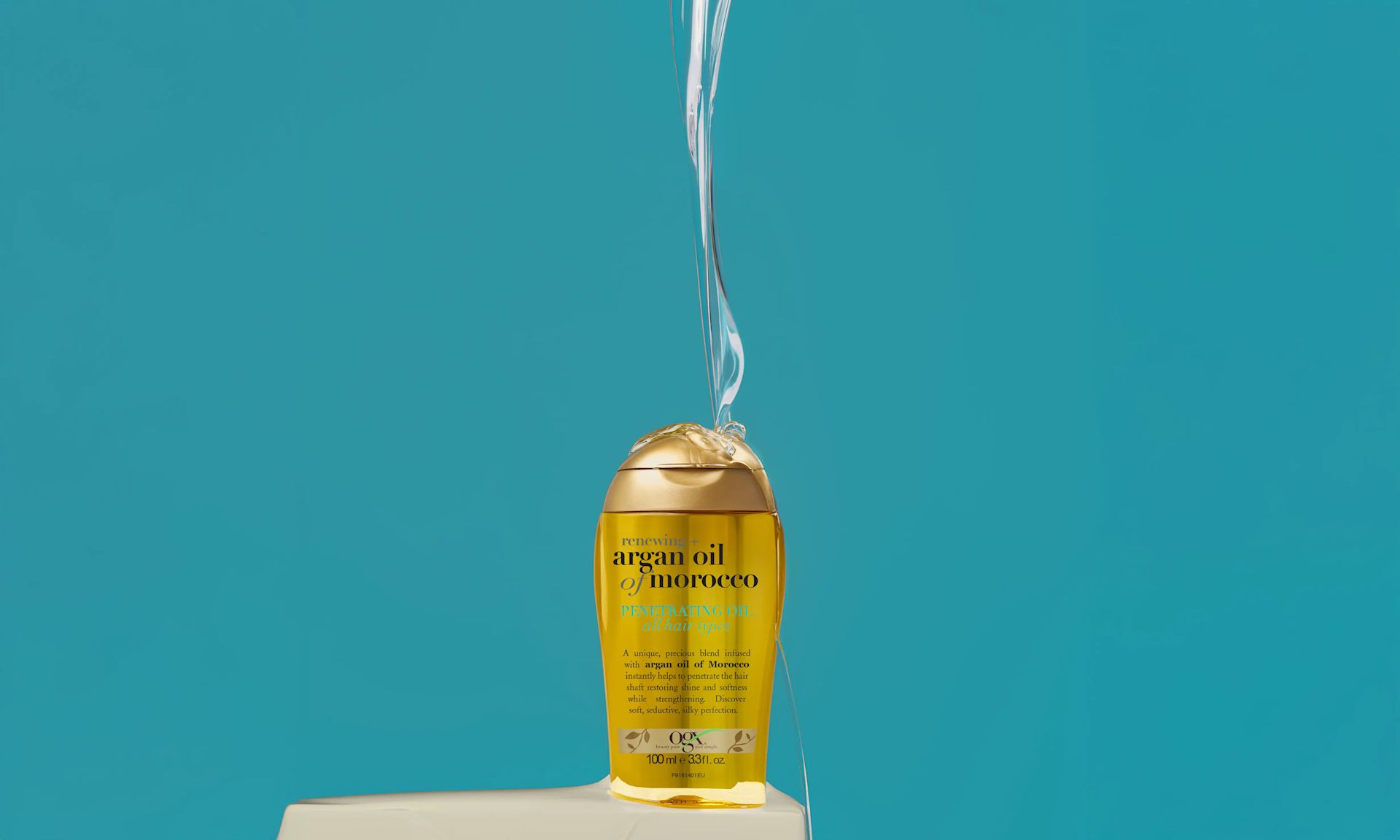 OGX® Argan Oil of Morocco Penetrating Oil being poured over a bottle of Penetrating Oil.