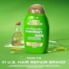 Vue avant du revitalisant extra fort romarin et menthe OGX® de 385 mL avec une éprouvette et une bouteille