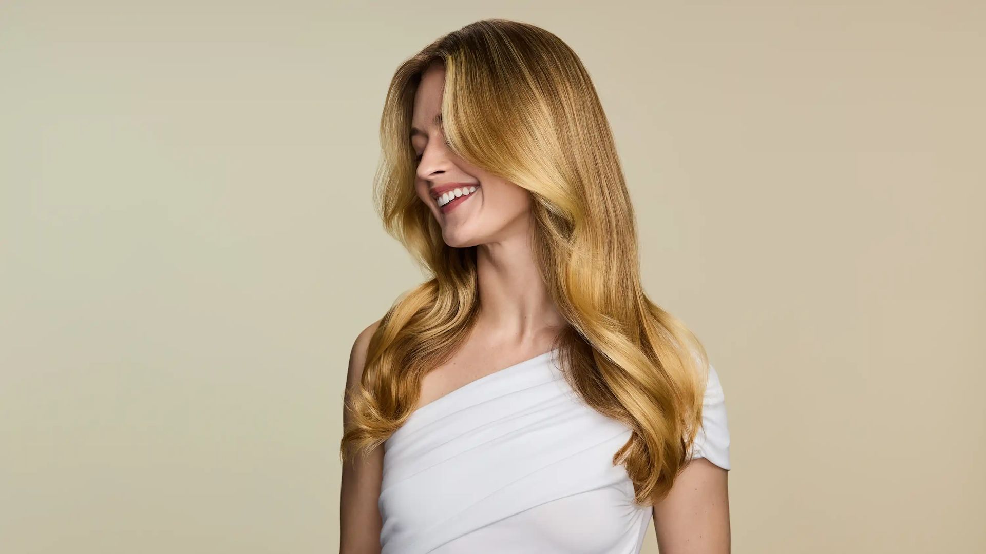 Smiling woman with straight hair after using OGX® Beauty products