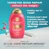 Front shot of OGX® Bond Protein Repair Shampoo, 385 mL next to the illustration of molecules and a laboratory  tube