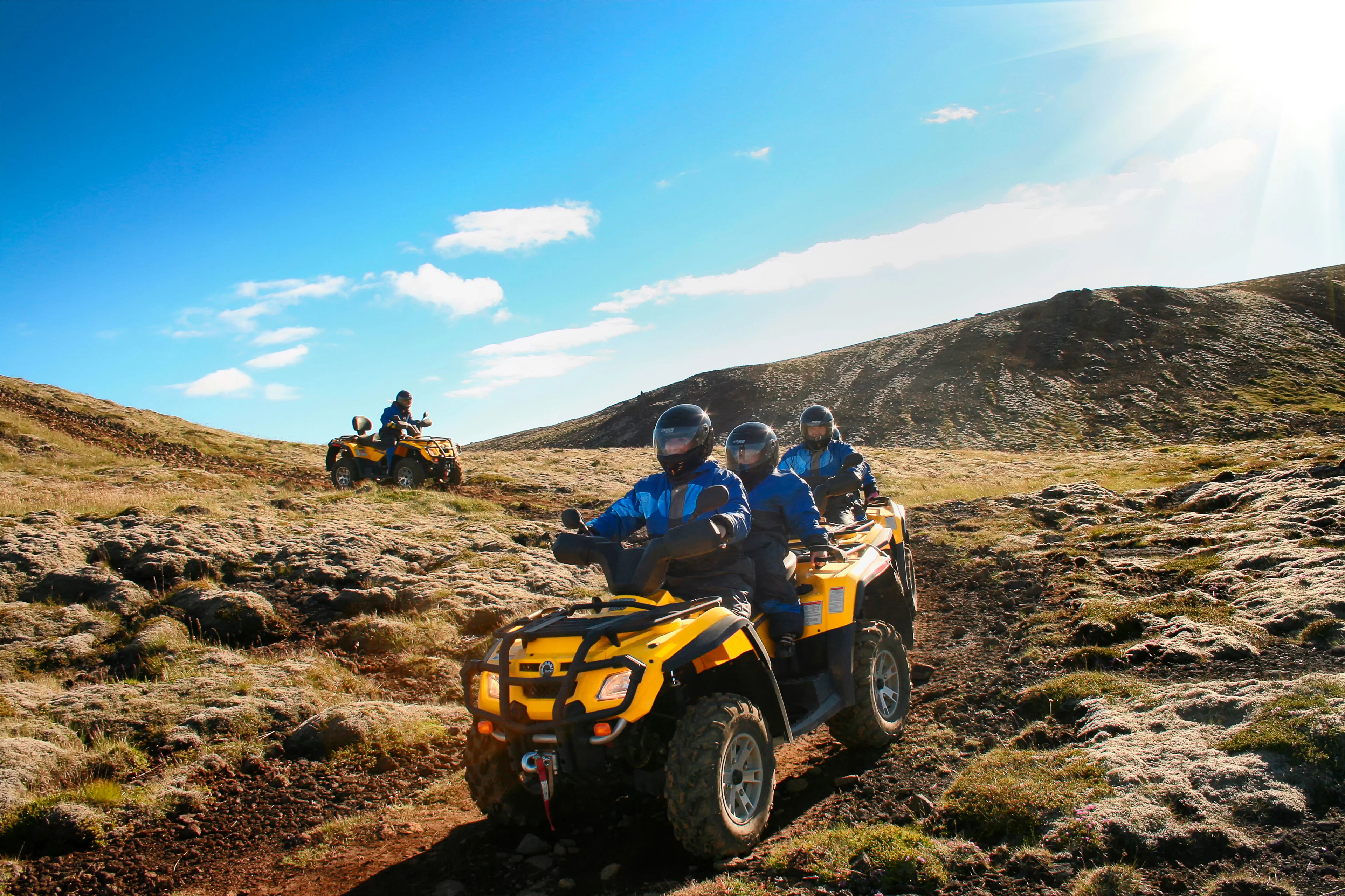 People riding all terrain vehicles across icelandic hillside