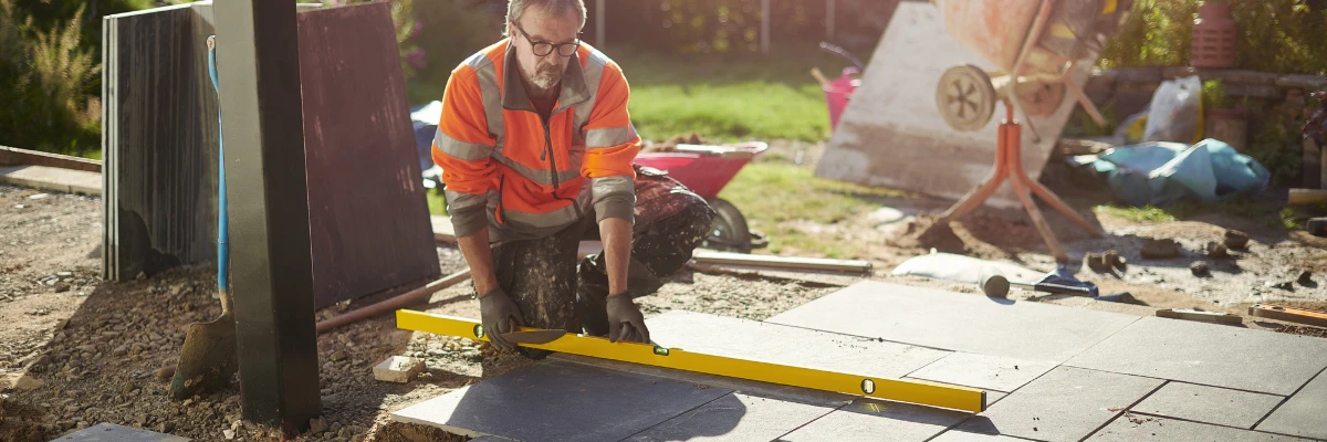 A builder checking a patio is level on a cement foundation.