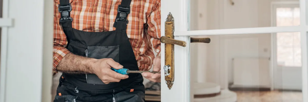 A locksmith adjusting a lock on a glass door.