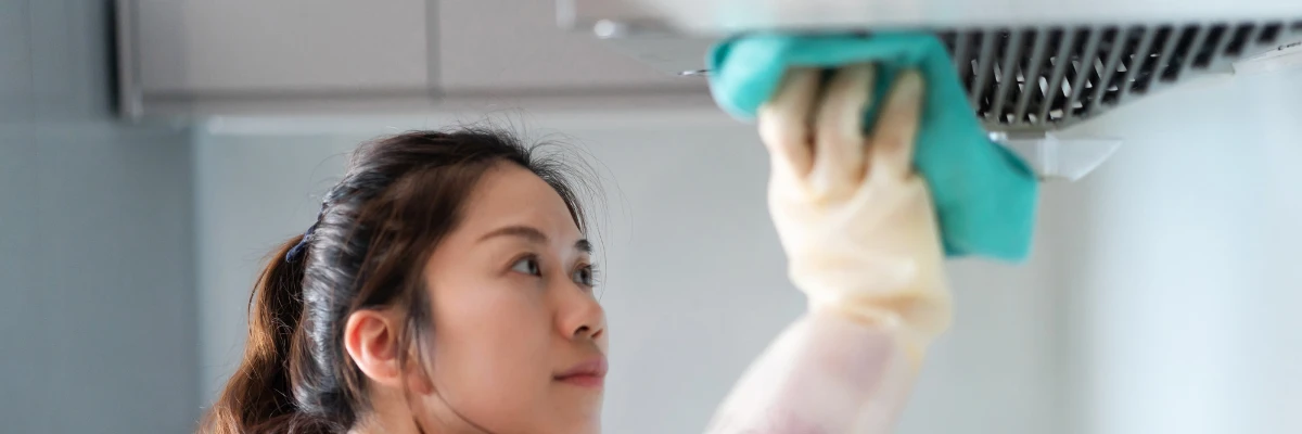A domestic cleaner cleaning a kitchen hood fan.