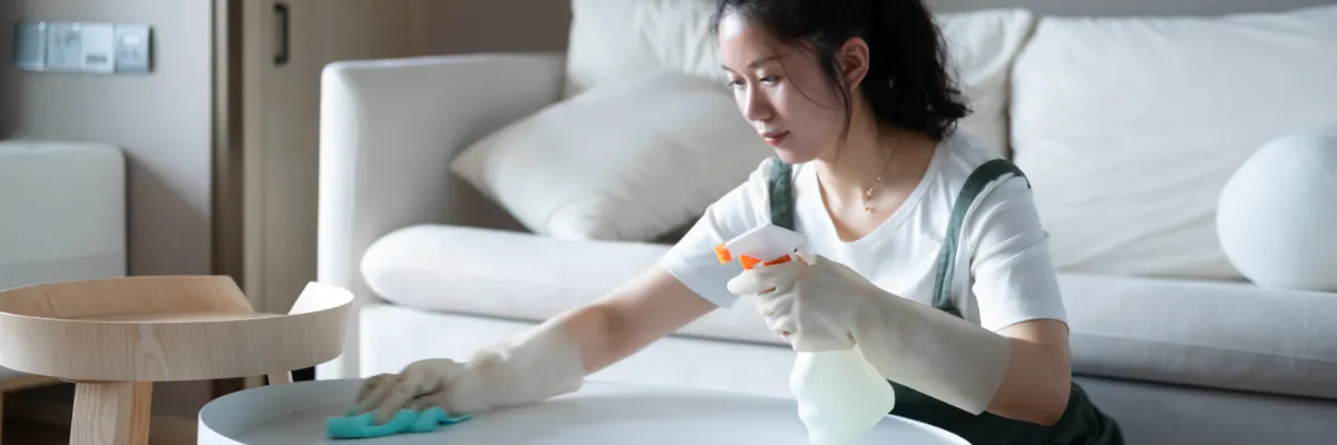 A cleaner wiping down a coffee table.
