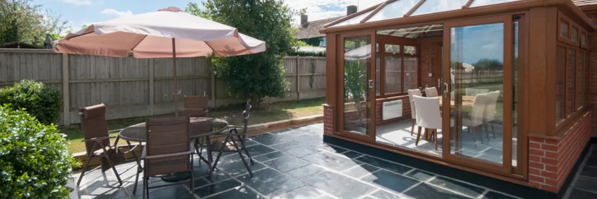 A modern wooden conservatory set upon a patio.