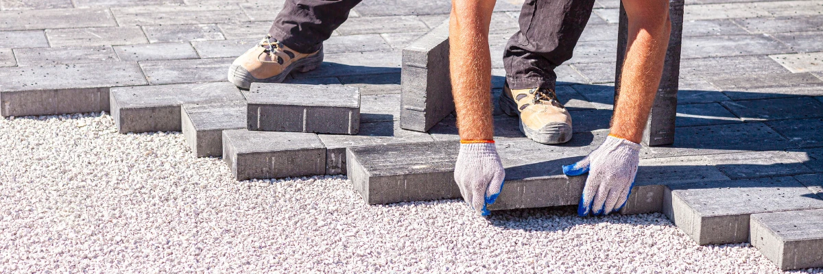 A paving professional laying paving blocks on aggregate.