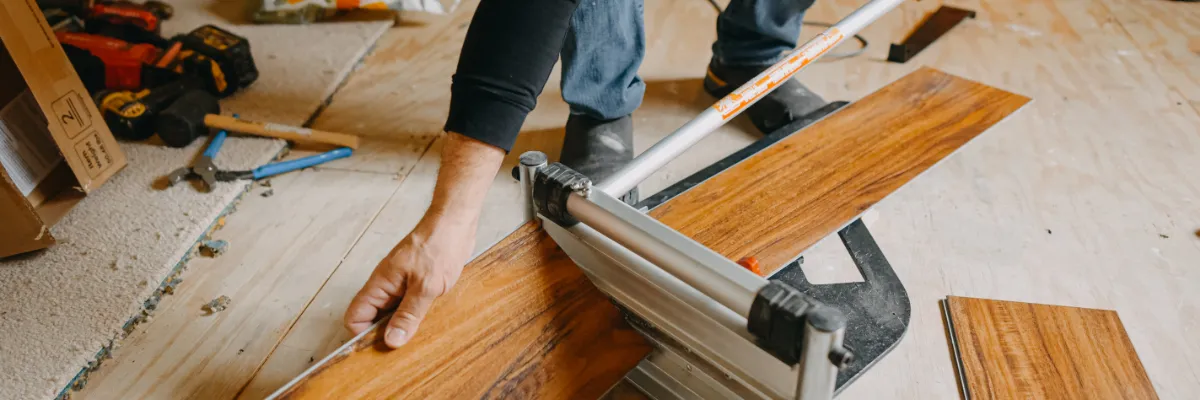 An installer measuring a plank of laminate flooring.