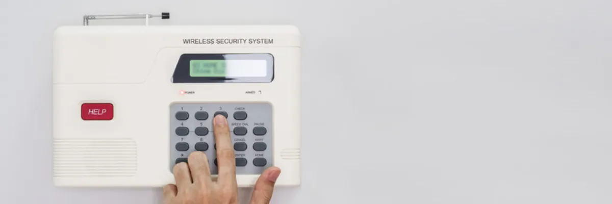 A person pressing a button on a wireless security system console.