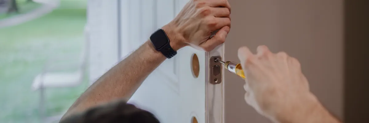 A handyman installing a latch on a door.