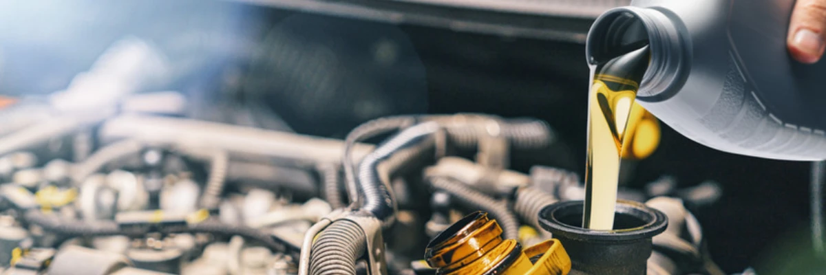 A mechanic pouring oil into a car's engine.