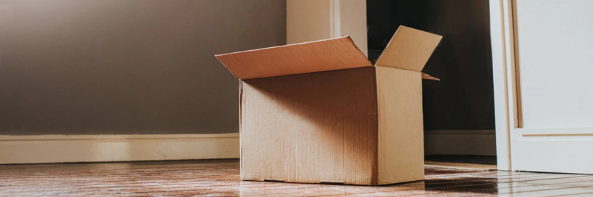 An open moving box placed in an empty room.