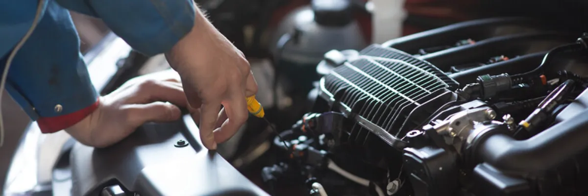 A mechanic assessing a car's engine with the hood up.
