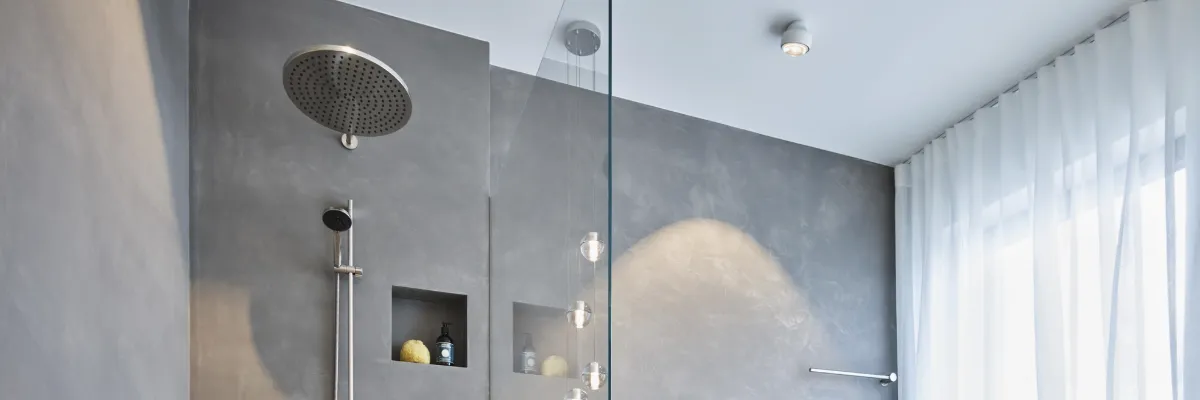 A modern, stainless steel shower in a grey bathroom.
