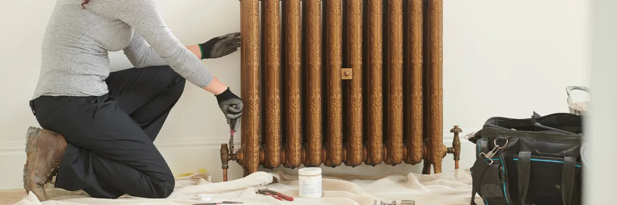 A heating engineer removing a brass radiator.