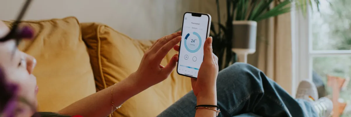 A woman adjusting her heating through a smartphone.