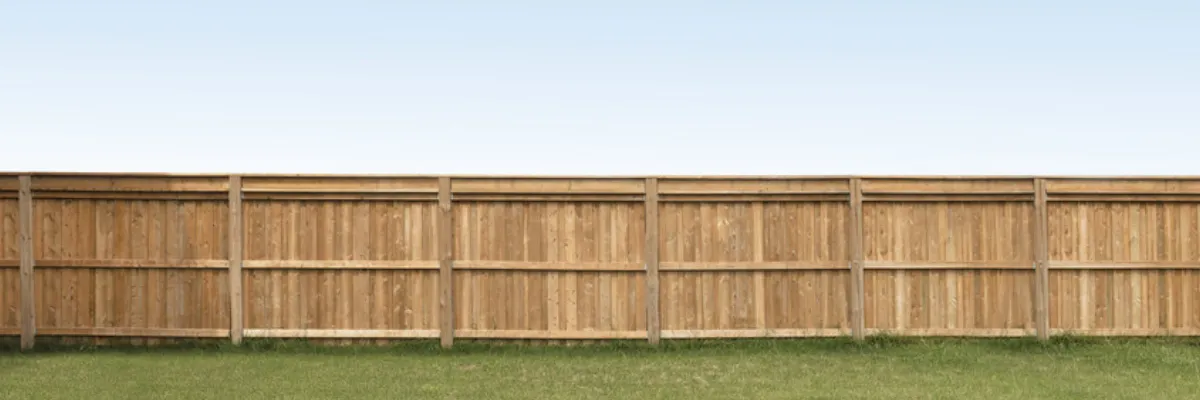 An unpainted wooden fence on a field of grass.