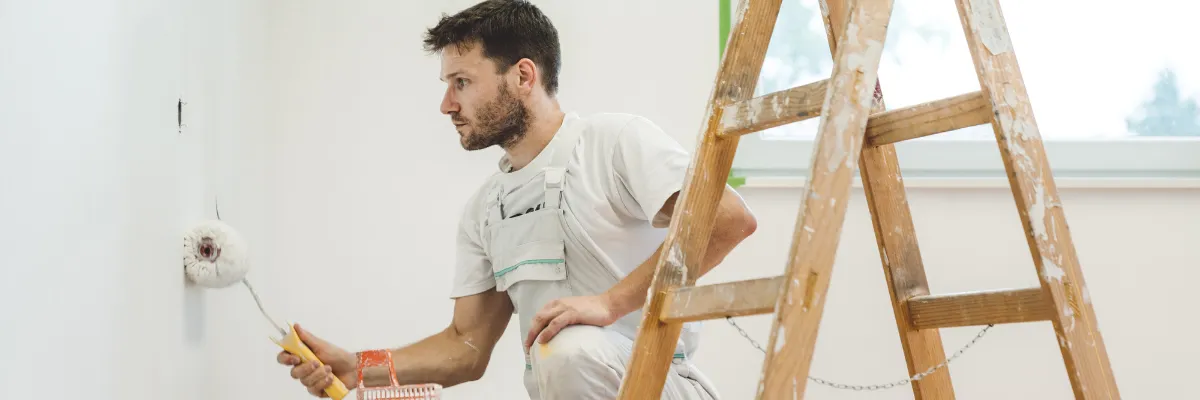 A person painting a wall white with a paint roller.