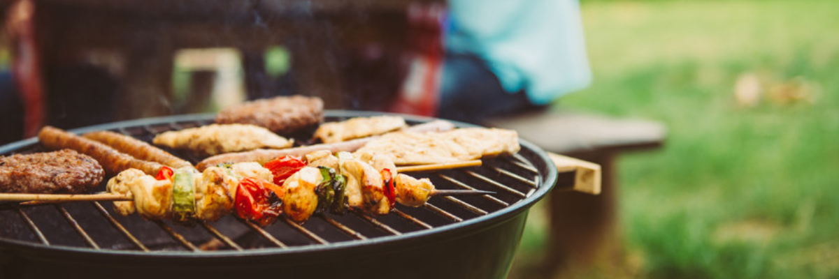 A variety of grilled food cooking on a round barbecue.