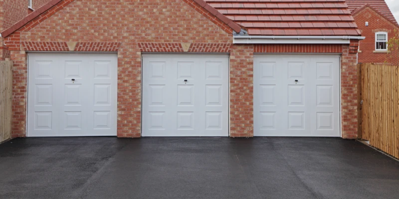 Asphalt Driveway Article Image An asphalt driveway leading up to a house's triple garage.