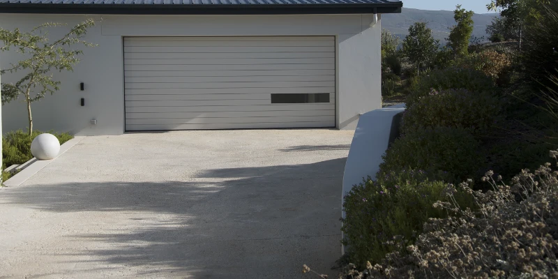 Concrete Driveway Article Image A concrete driveway leading up to a house's garage.