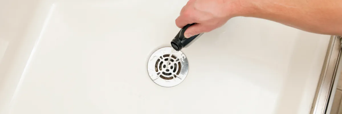 Someone pouring drain unblocker down a shower drain.