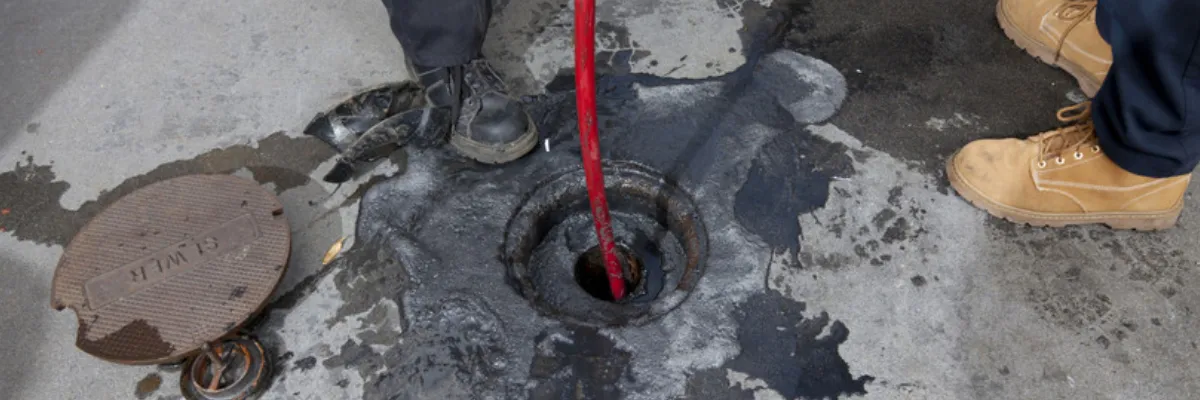 A pair of drainage specialists clearing a sewer line with high-pressure jetting.
