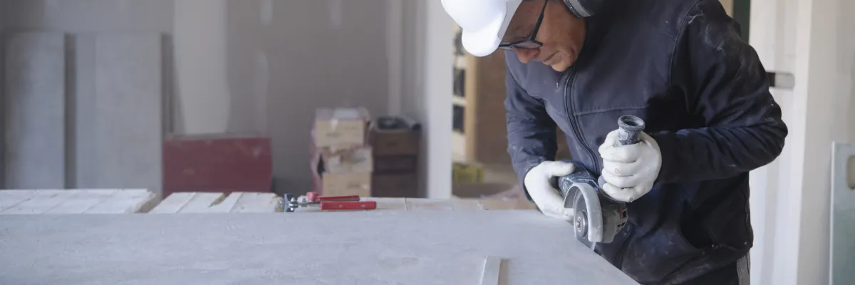 A builder cutting a piece of plasterboard.