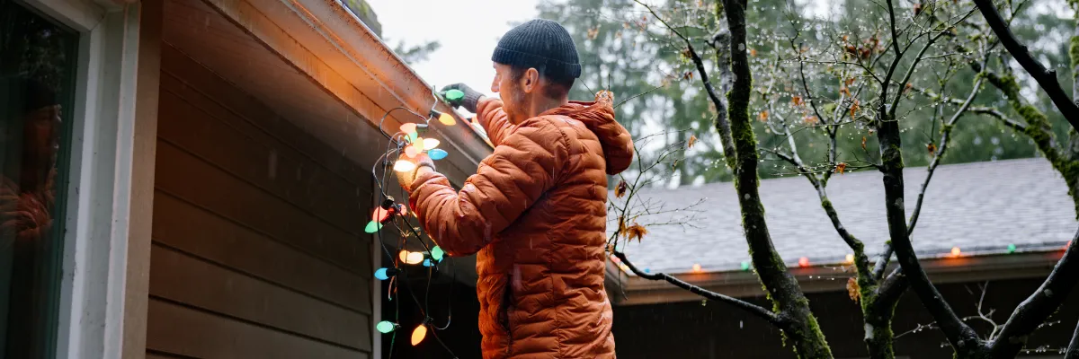 man hanging colourful Christmas lights