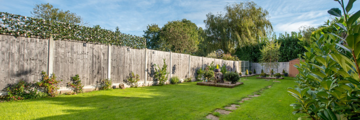A long garden with a vibrant lawn, with a paved path running down the centre of the garden.