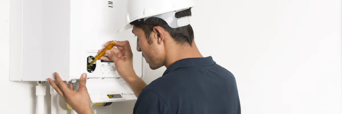A boiler installing adjust a newly fitted boiler with a screwdriver.