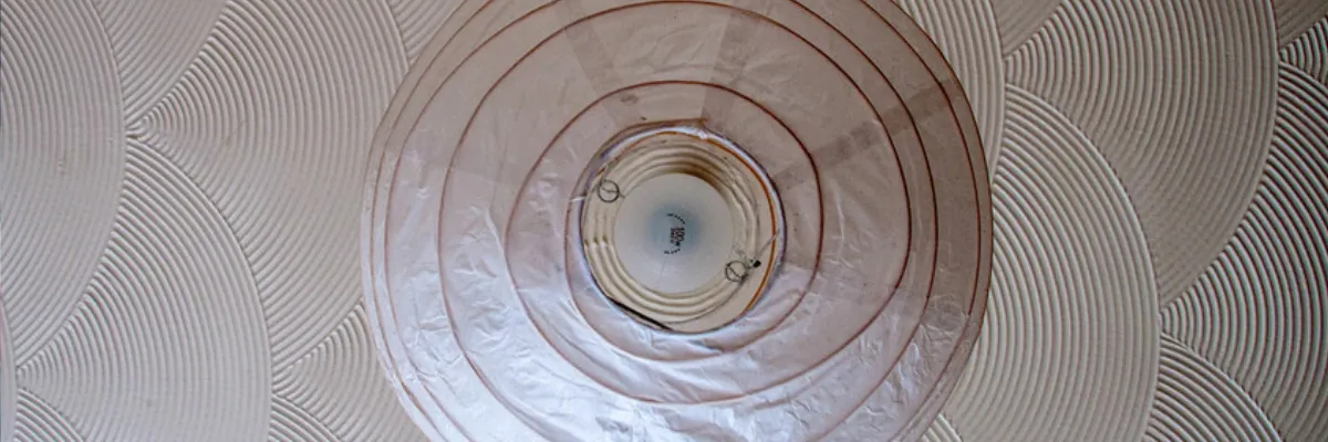 An Artex ceiling with a light fitting hanging beneath it, as seen from below.