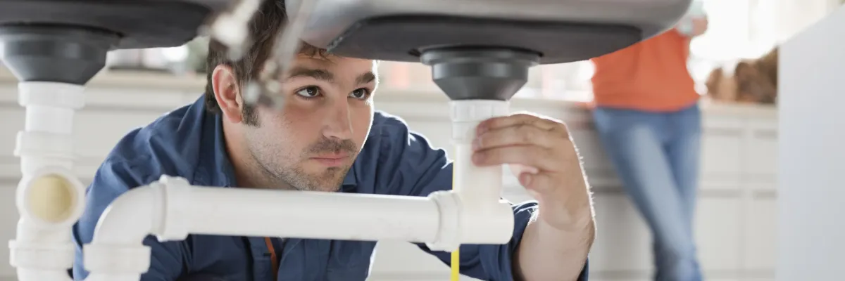 A plumber unblocking a sink with a plunger.