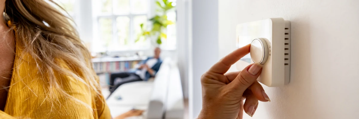 A woman adjusting a thermostat dial.