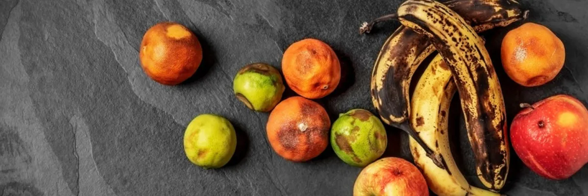 A mix of rotting fruit, including bananas, apples, and oranges.
