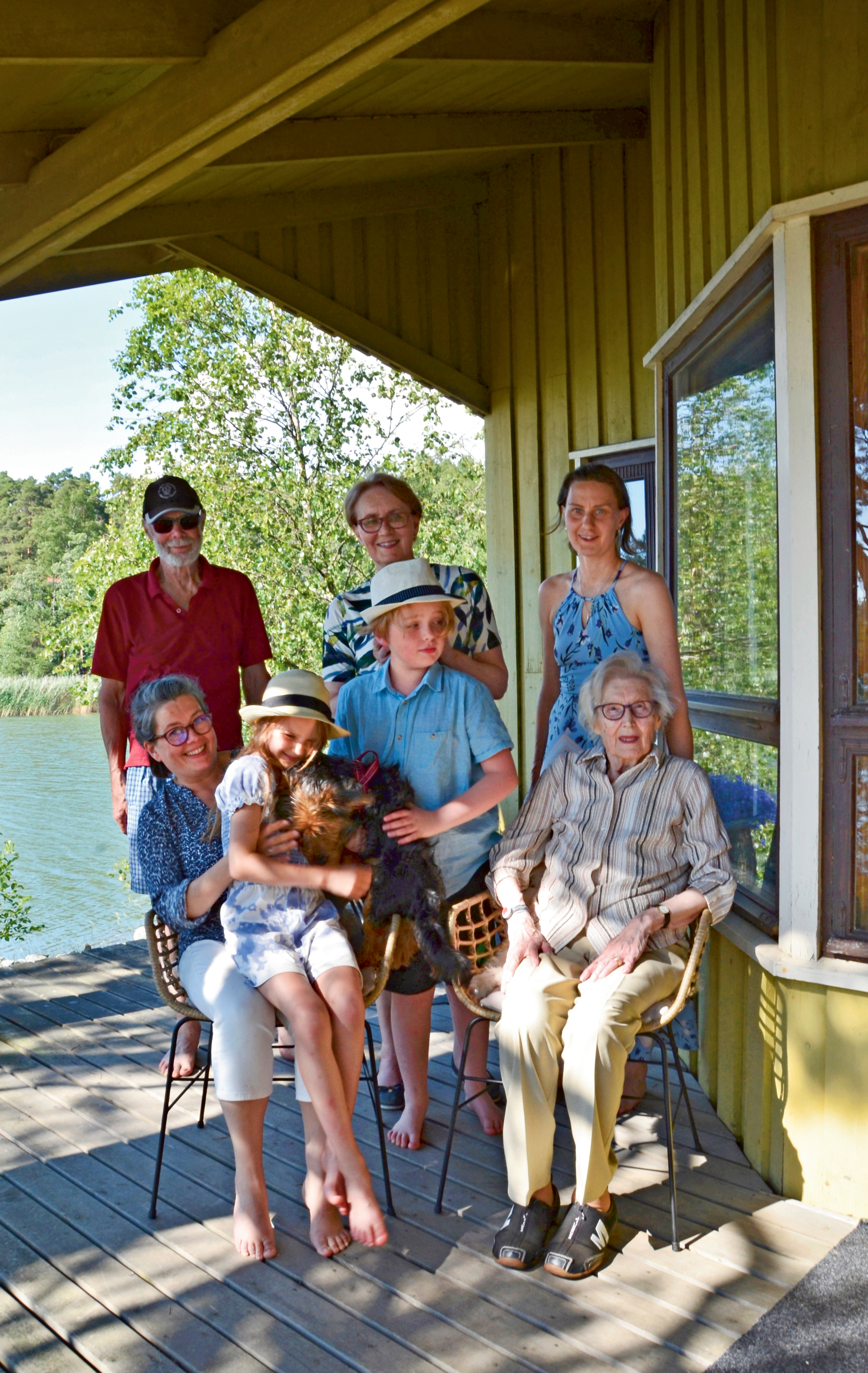 monta sukupolvea ryhmäkuvassa mökin terassilla
