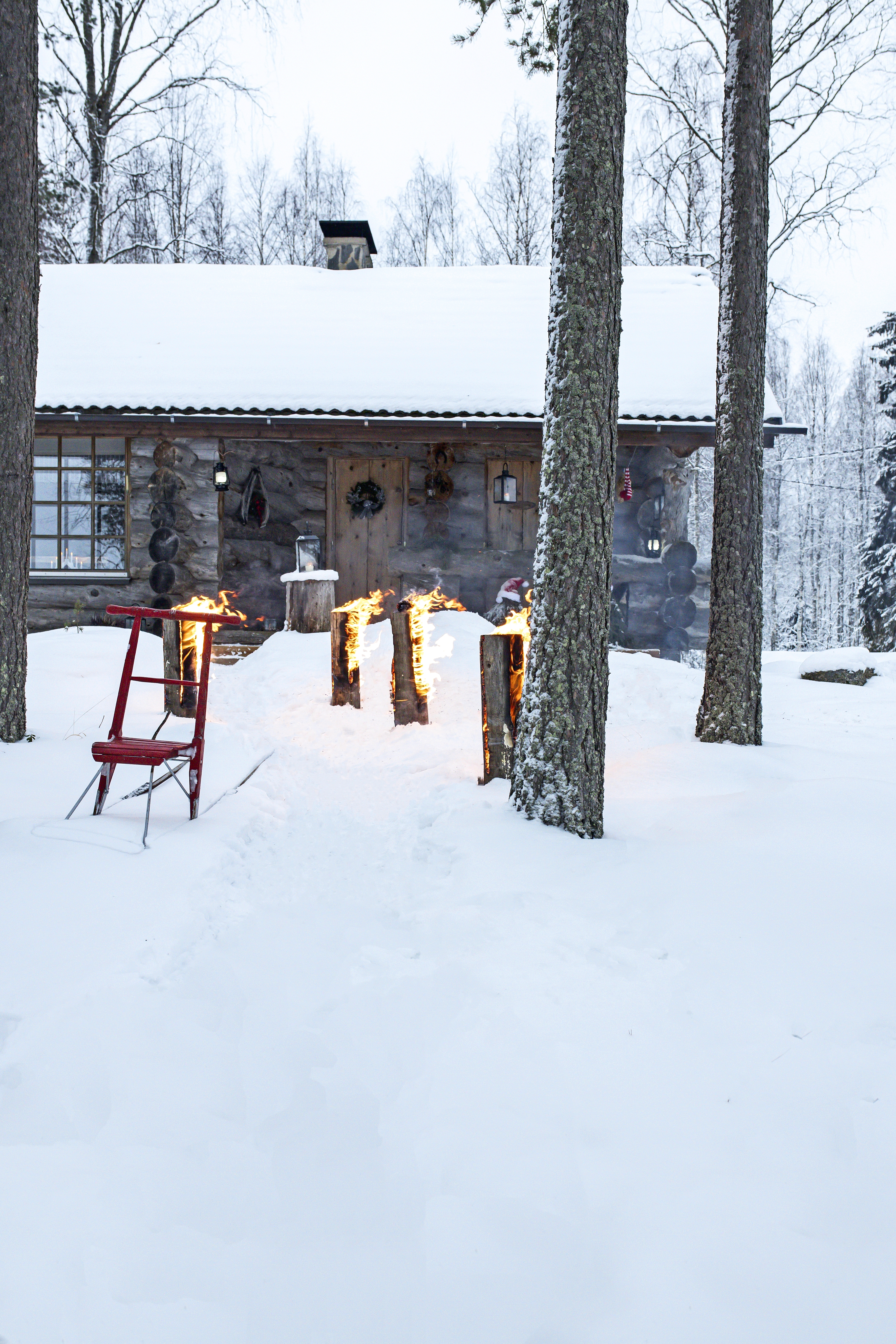Jätkänkynttilöitä palaa hangessa kelomökin edessä.