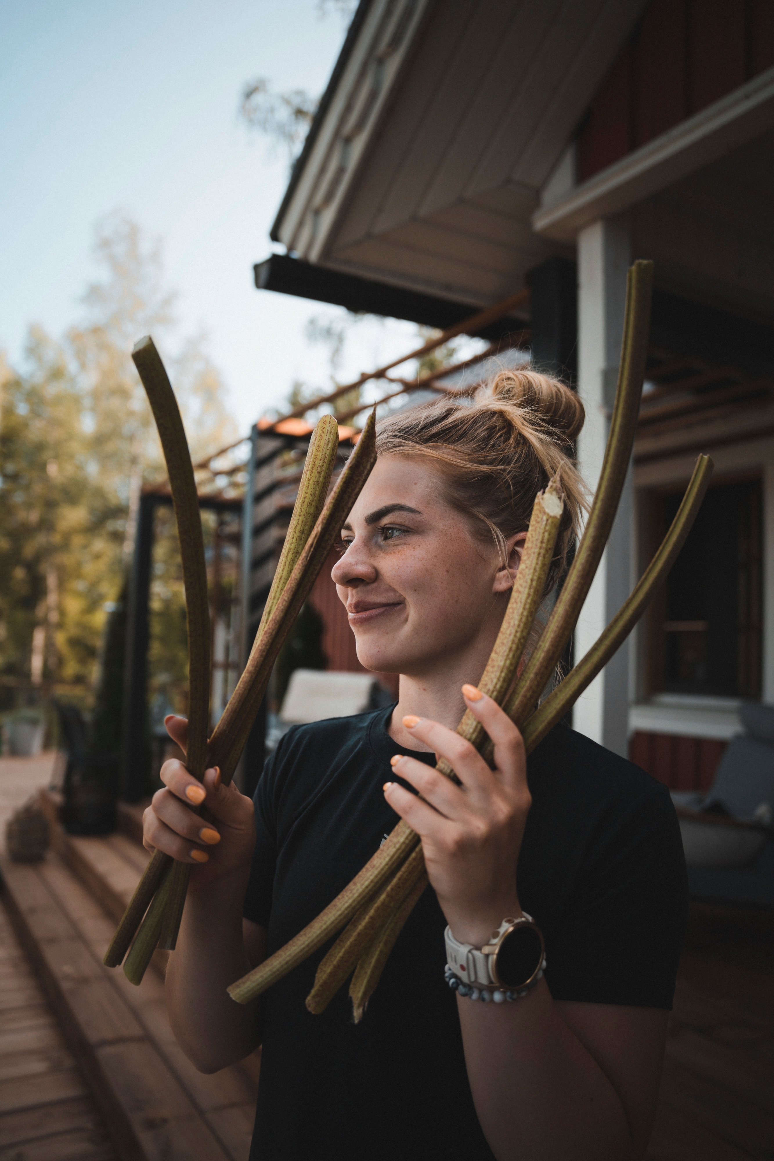 Pernilla Böckerman raparperinvarsia käsissään mökin edessä