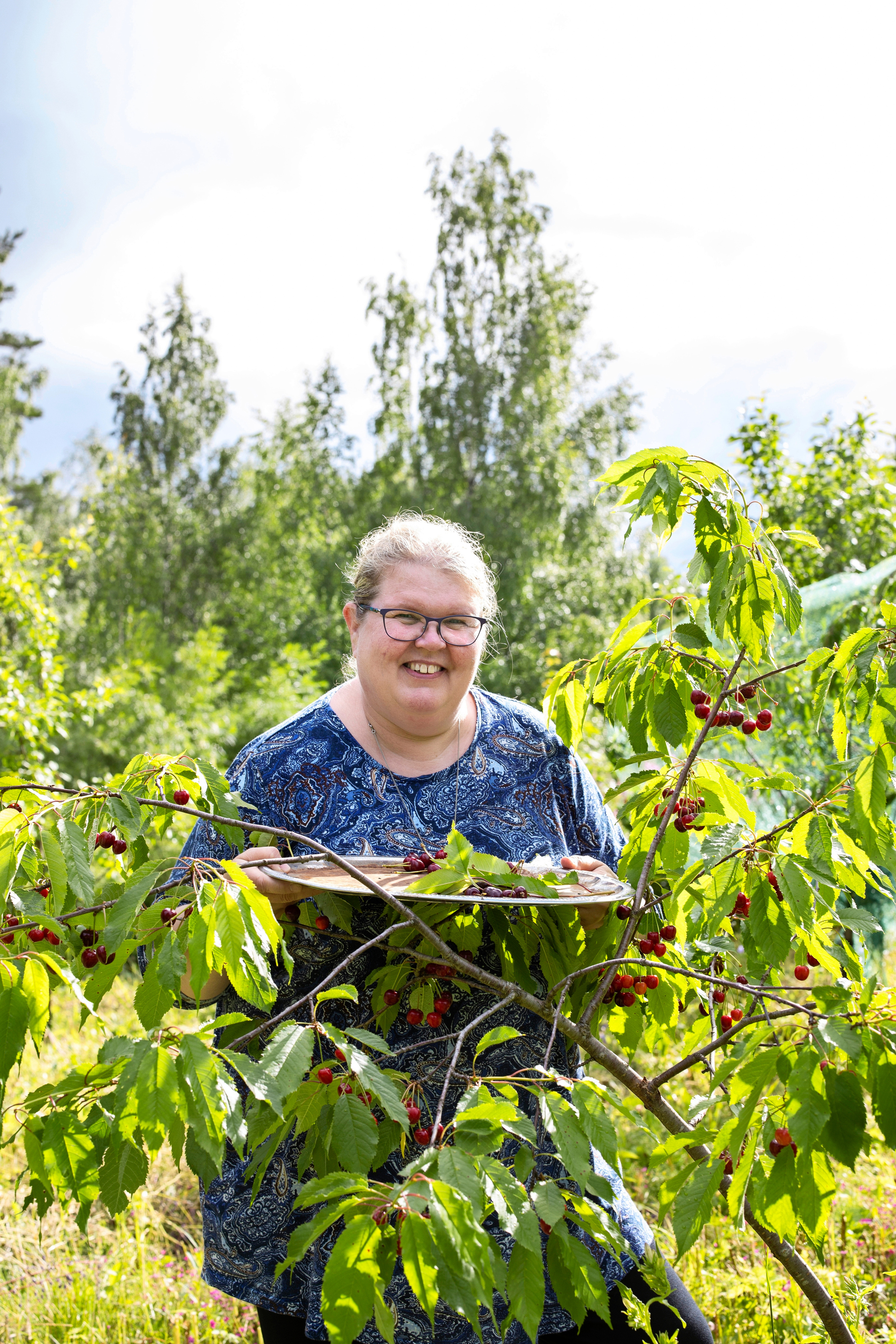 Sirpa Iivari hymyilee kirsikkapuun takaa