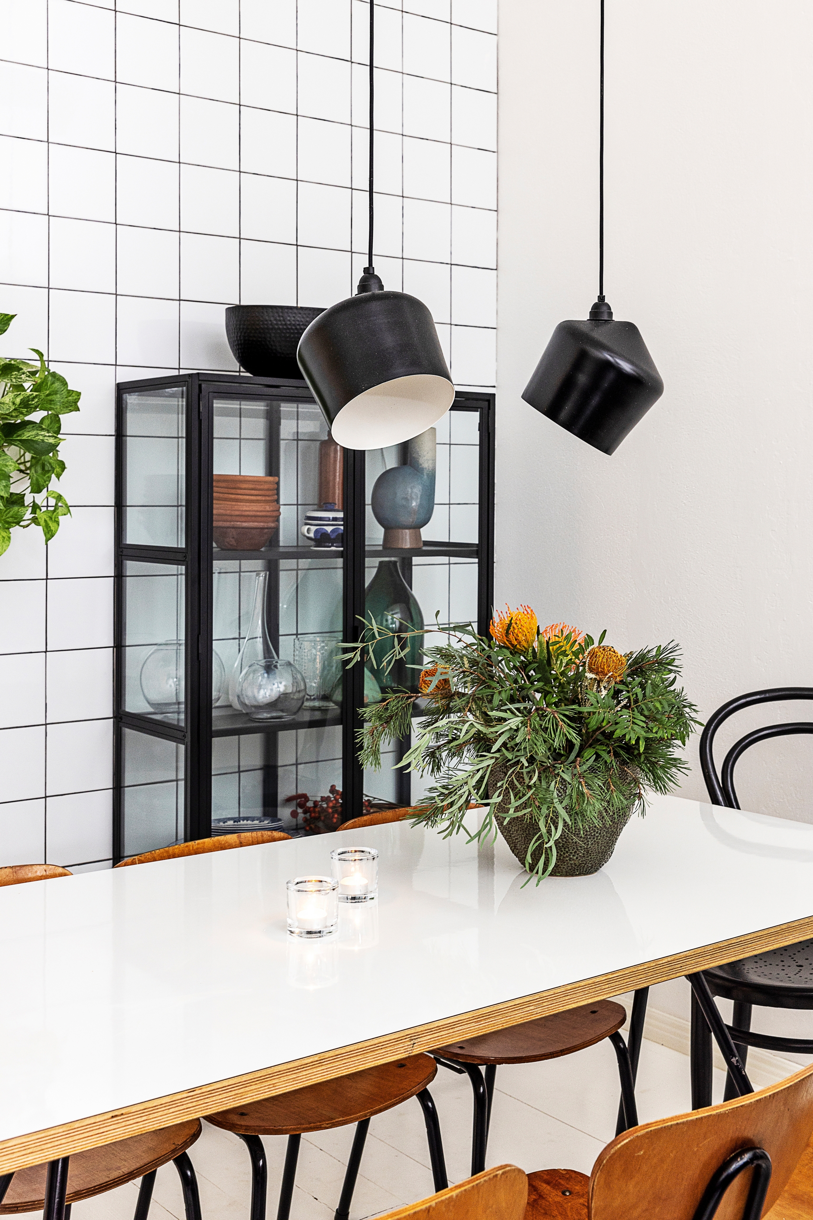 Square tiles with black grout behind a black-framed display cabinet