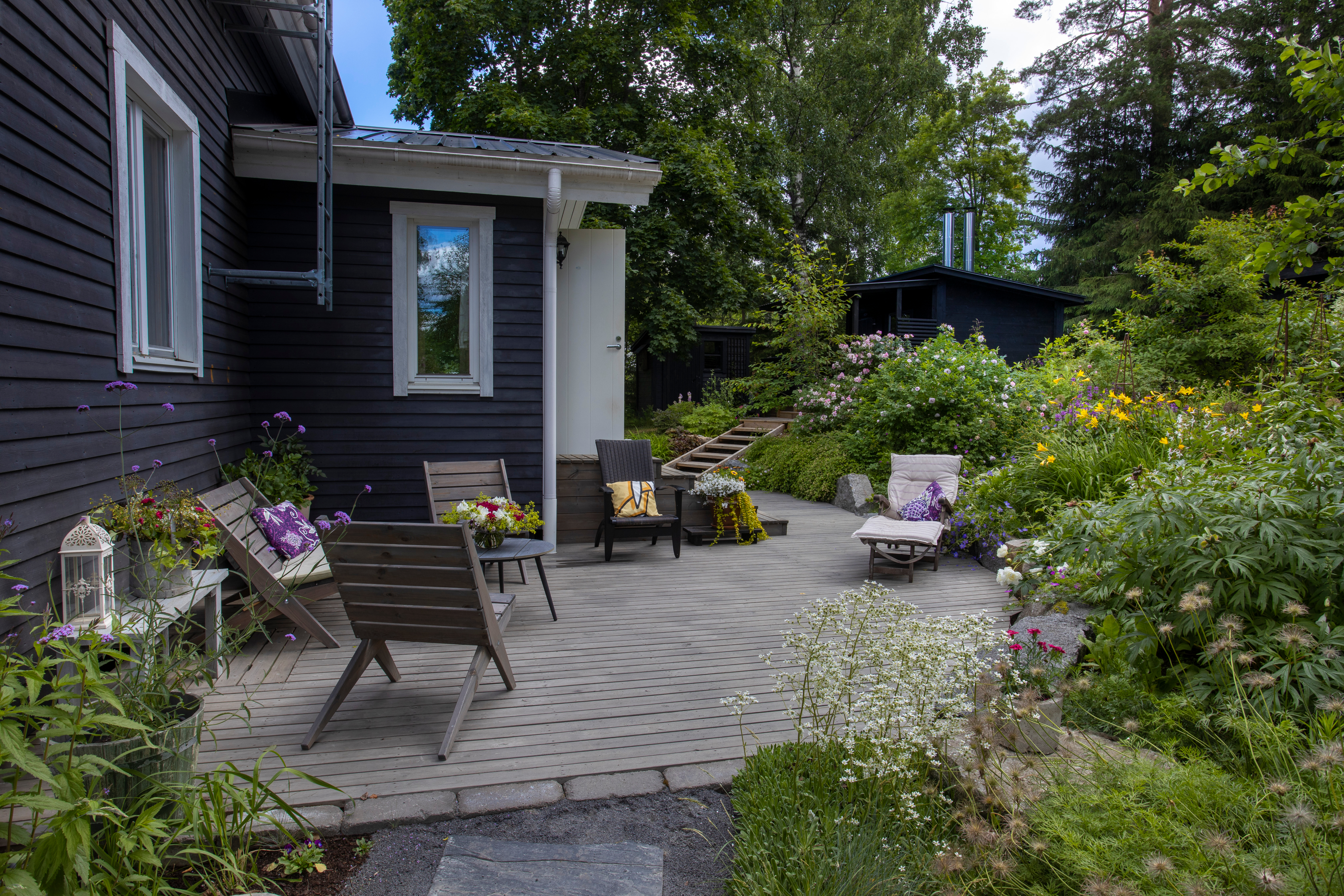 Suuret graniittilohkareet rajaavat etupihan ison kasviryhmän talon edustan kestopuupatiosta.