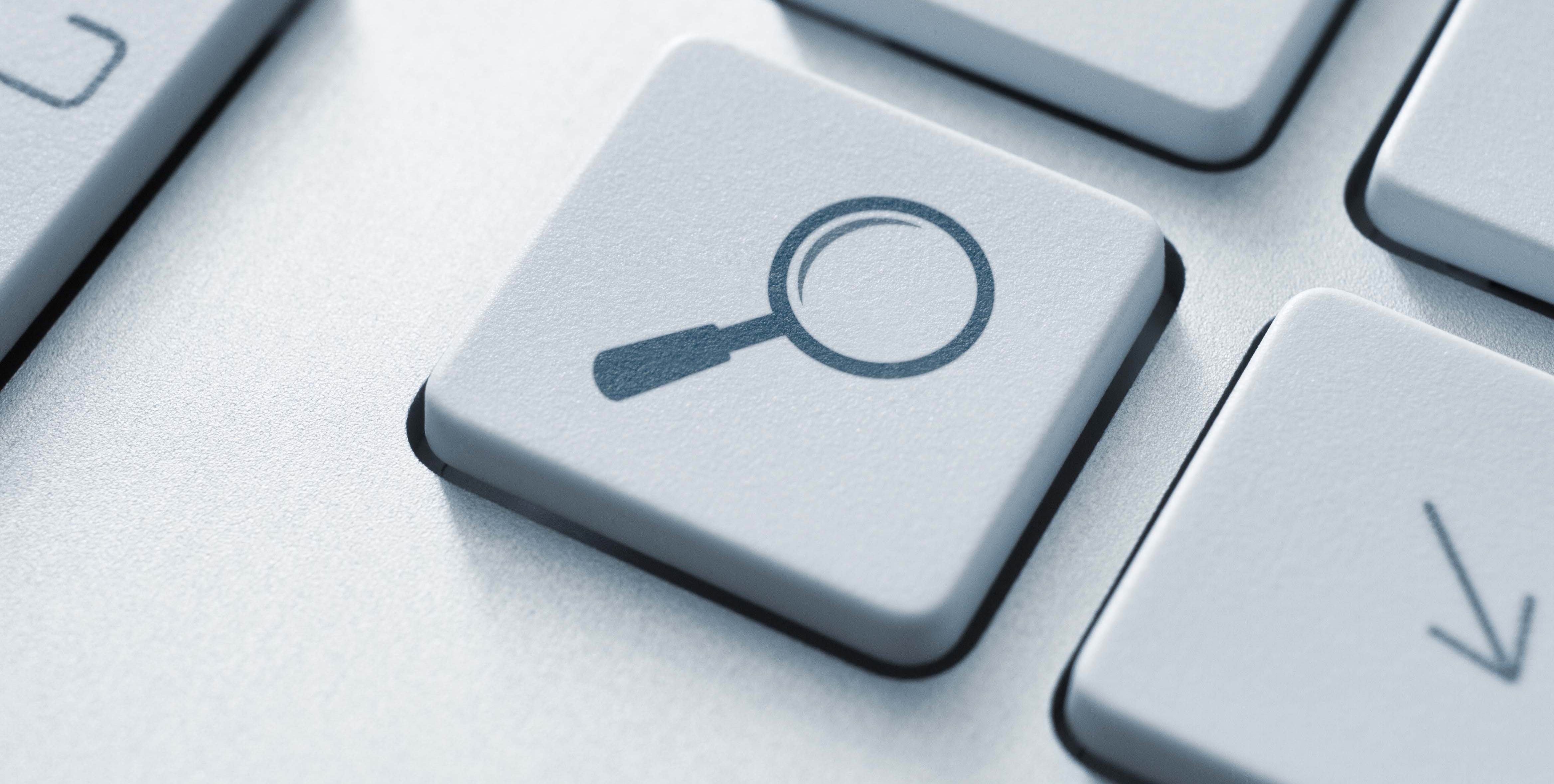 A computer keyboard key with a magnifying glass icon instead of a letter.
