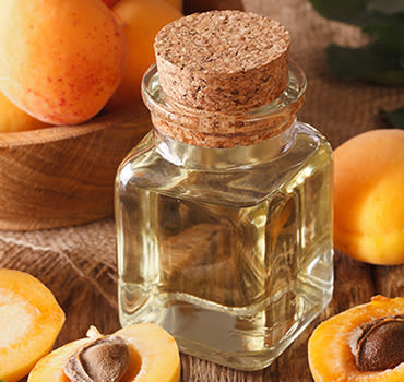 Apricot kernel oil in a glass jar closeup on the table and ingredients