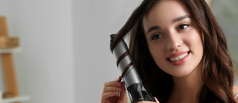 Caucasian woman using a curling iron in front of a mirror