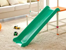 Pequeño tobogán de plástico verde en una sala de estar alfombrada