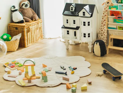 A child's playroom with dollhouse, stuffed animals, blocks, skateboard