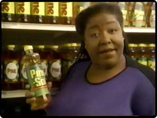 Diane Amos holding vintage Pine-Sol bottle near a shelf of products.