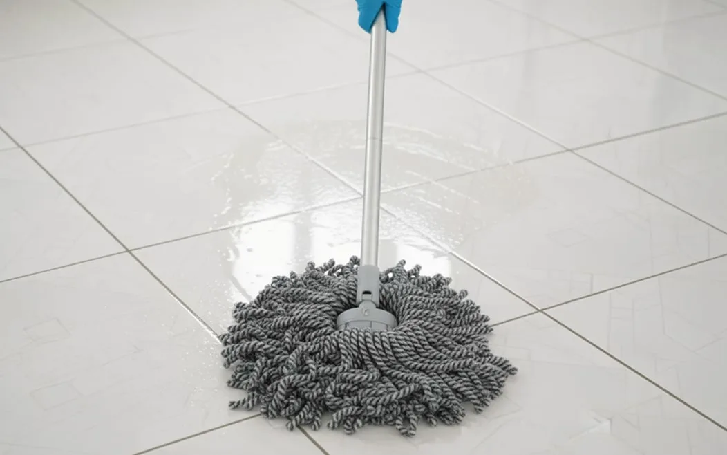 Una mopa circular gris que se utiliza en un piso de baldosas blancas.